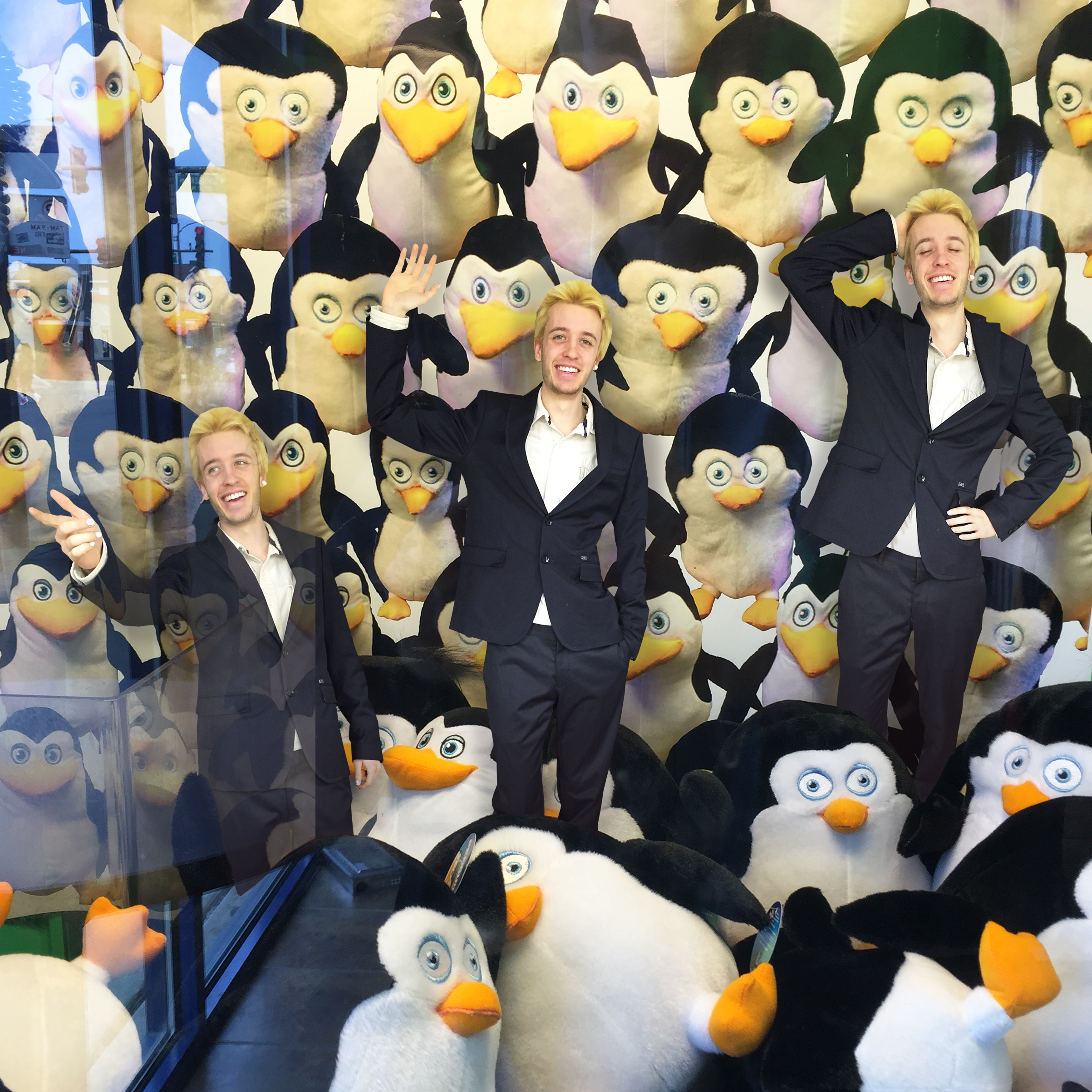 Three butlers posing and smiling in a toy dispenser machine full of penguin plush toys